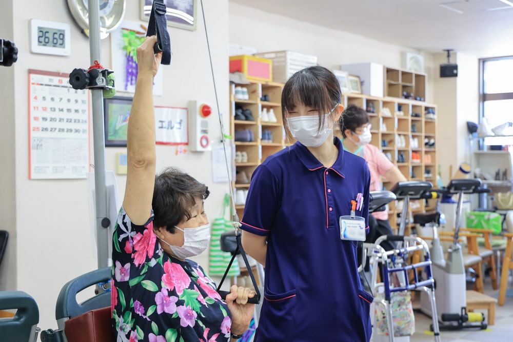 ご利用者さまのトレーニングを笑顔で補助するスタッフの様子