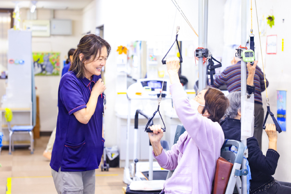 ご利用者さまのトレーニングを笑顔で補助するスタッフの様子