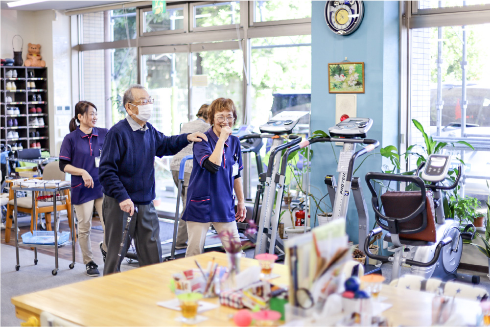 ご利用者さまのトレーニングを笑顔で補助するスタッフの様子